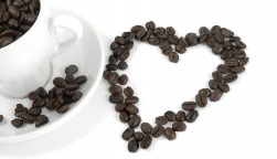 cup of coffe and coffee beans arranged in the shape of a heart