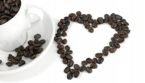 cup of coffe and coffee beans arranged in the shape of a heart