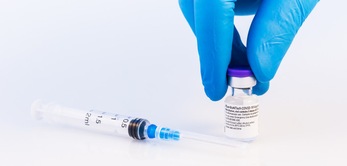 Doctor or scientist holding Pfizer-BioNTech Covid-19 vaccine on a white background.