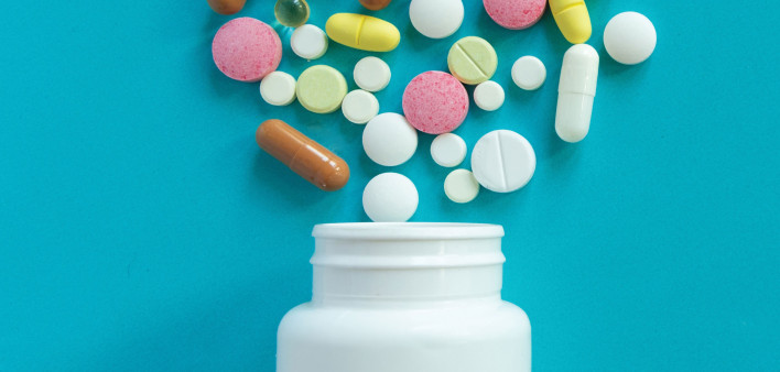 mulit colored pills spilled out of white bottle