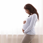 Beautiful pregnant afro woman hugging her tummy,