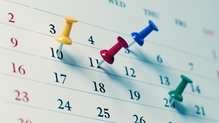 White calendar with colored push pins reminding important dates