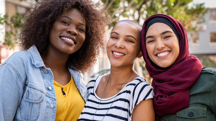 Group of three happy multiethnic friends looking at camera.