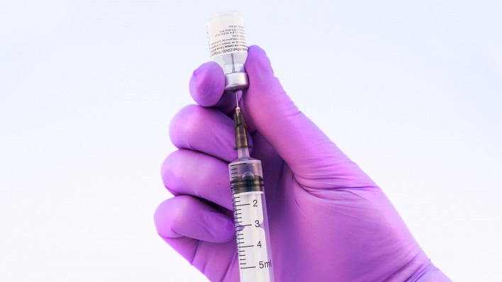 Doctor using Pfizer-BioNTech Covid-19 vaccine on a white background.