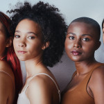 Black women tudio shot of a group of beautiful young women posing together against a gray background