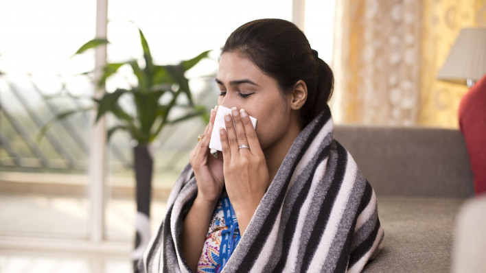 woman at home blowing nose tissue
