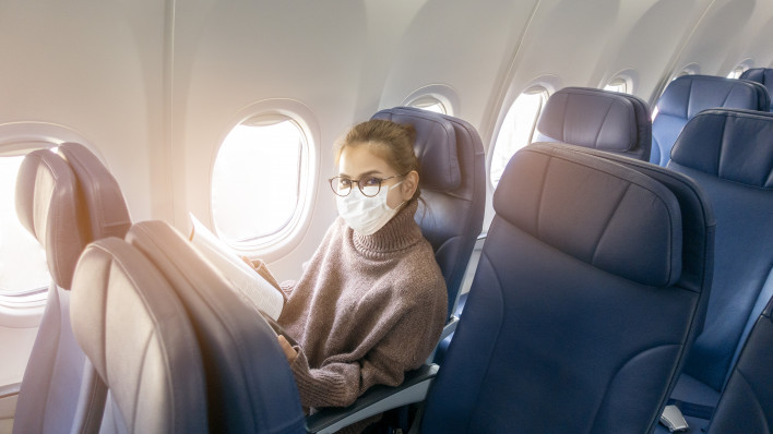 A young woman wearing face mask is traveling on airplane , New normal travel after covid-19 pandemic