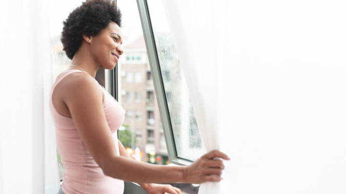 Happy black woman looking out through window