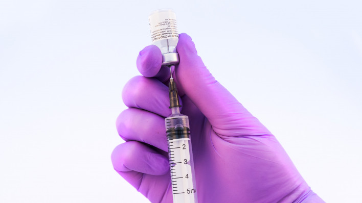 Doctor using Pfizer-BioNTech Covid-19 vaccine on a white background.