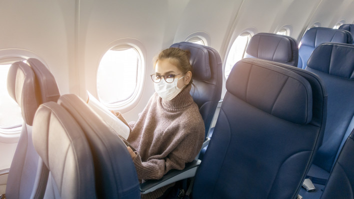 A young woman wearing face mask is traveling on airplane , New normal travel after covid-19 pandemic