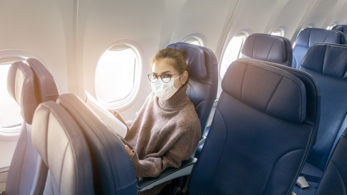 A young woman wearing face mask is traveling on airplane , New normal travel after covid-19 pandemic