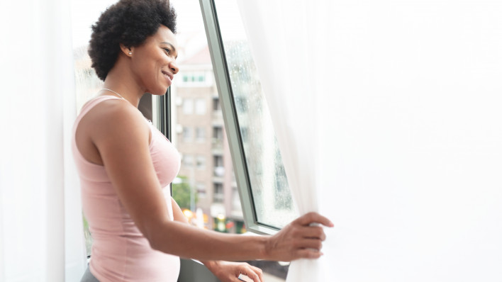 Happy black woman looking out through window