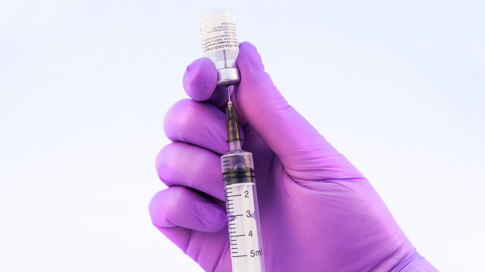 Doctor using Pfizer-BioNTech Covid-19 vaccine on a white background.