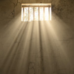 light shining through bars of prison window 