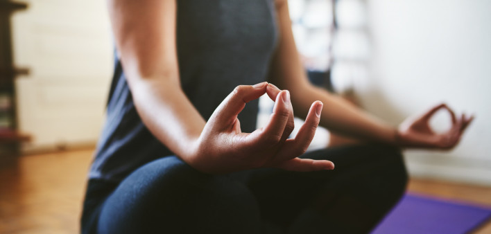 Cropped shot of an unrecognizable woman sitting on a yoga mat and meditating alone in her home