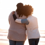 mom and daughter hugging on the beach