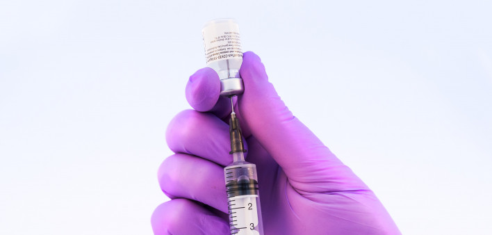 Doctor using Pfizer-BioNTech Covid-19 vaccine on a white background.