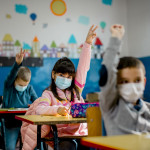 Elementary schoolchildren wearing a protective face masks in the classroom. Education during epidemic.