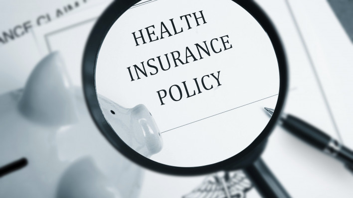 A maginfying glass looking at the words "Health Insurance Policy"