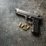 9mm pistol bullets and handgun on black table.