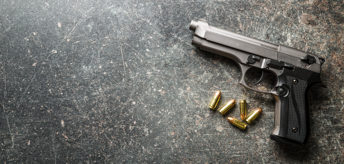 9mm pistol bullets and handgun on black table.