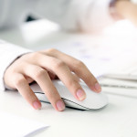 Closeup shot of female hand holding mouse and working with desktop computer