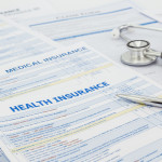 Medical insurance application, silver pen and stethoscope. Legal law contract and health insurance concepts.