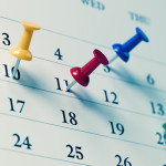 White calendar with colored push pins reminding important dates