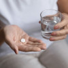hands holding pill and glass of water