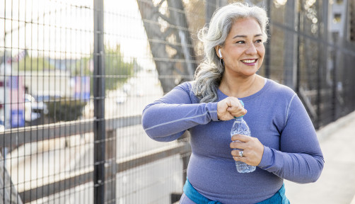 A senior Mexican woman drinking water after a workout