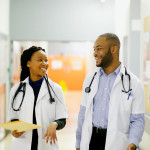 Two young African-American doctors having a laugh in the corridor walking Cape Town South