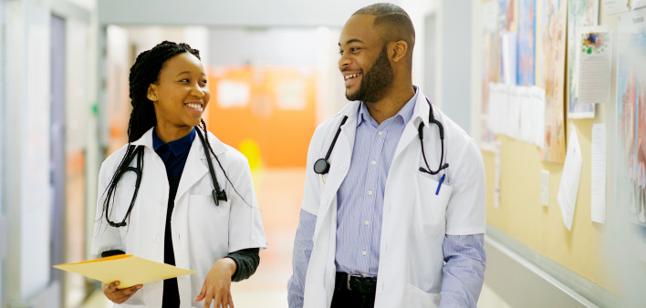 Two young African-American doctors having a laugh in the corridor walking Cape Town South