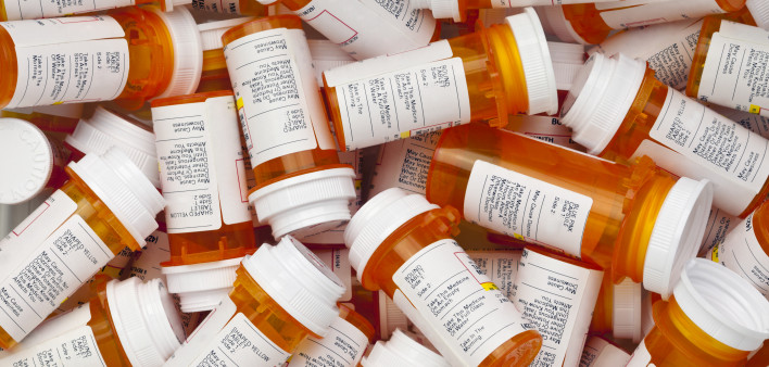Dozens of prescription medicine bottles in a jumble. This collection of pill bottles is symbolic of the many medications senior adults and chronically ill people take.