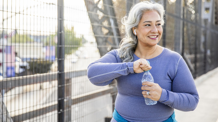 A senior Mexican woman drinking water after a workout