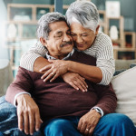 Cropped shot of a cheerful elderly woman hugging her husband who's in a wheelchair at home during the day
