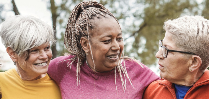group of older women outside arm in arm smiling