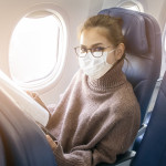 A young woman wearing face mask is traveling on airplane , New normal travel after covid-19 pandemic