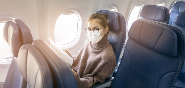 A young woman wearing face mask is traveling on airplane , New normal travel after covid-19 pandemic
