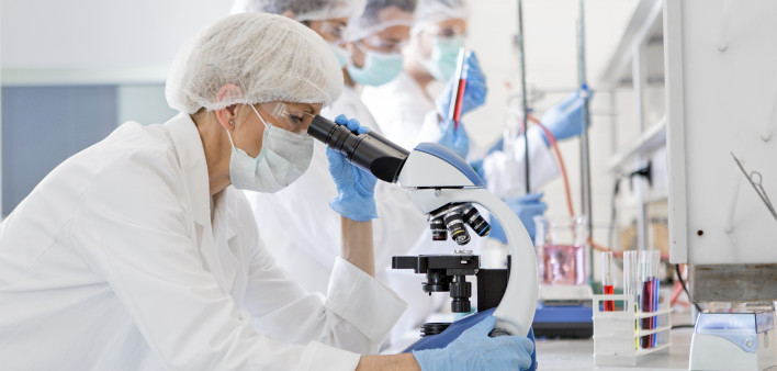 Scientists in protective suits in a science laboratory study a virus