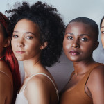 Black women tudio shot of a group of beautiful young women posing together against a gray background