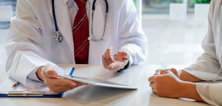 Doctor and female patient discussing while using digital tablet at hospital.