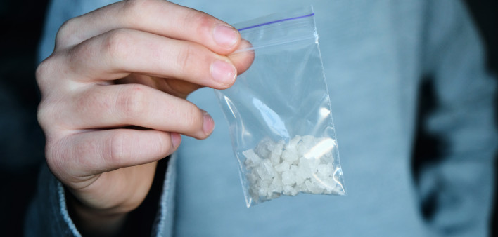 Hand holds packet with white narcotic - cocaine, meth or another drug