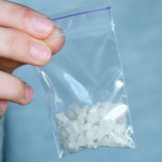 Hand holds packet with white narcotic - cocaine, meth or another drug