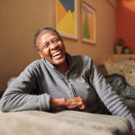African American Black woman laughing on couch