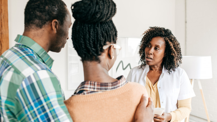 doctor having discussion with couple, the man has his arm around the woman