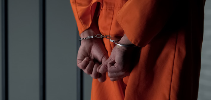 Prisoner with handcuffed arms behind back, another jail transfer, criminal