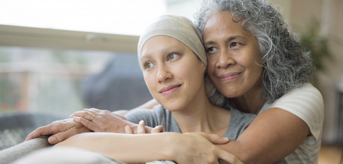 Ethnic young adult female cancer patient hugged by her mother
