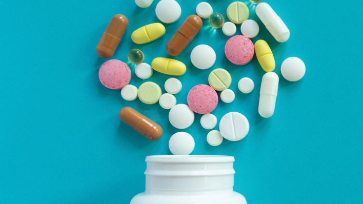 mulit colored pills spilled out of white bottle
