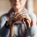 old woman, her hands resting on a cane