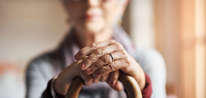 old woman, her hands resting on a cane